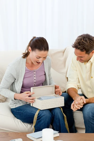 Amazed woman opening a present from his boyfriend on the sofa — Stock Photo, Image