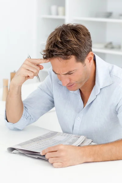 Concentrated man doing a cryptic crossword sitting in his kitche — Stock Photo, Image