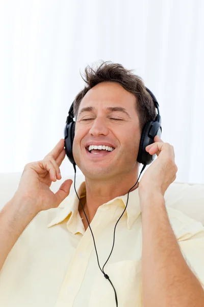 소파에서 음악을 듣고 노래 하는 행복 한 사람 — 스톡 사진