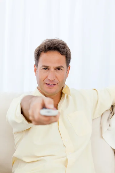 Relaxed man pointing a remote to the camera — Stock Photo, Image