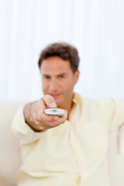Primer plano de un hombre sosteniendo un mando a distancia en el sofá —  Fotos de Stock