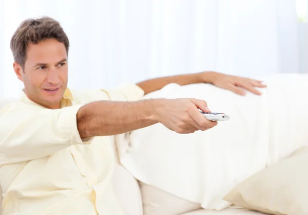 Handsome man changing channel sitting on the sofa — Stock Photo, Image