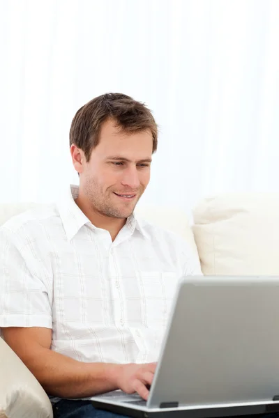 Homem feliz trabalhando em seu laptop no sofá — Fotografia de Stock