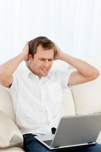 Tense man working on his laptop sitting on the sofa — Stock Photo, Image