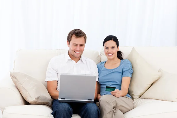 Heureux couple achetant en ligne avec ordinateur portable et carte de crédit sur le so — Photo