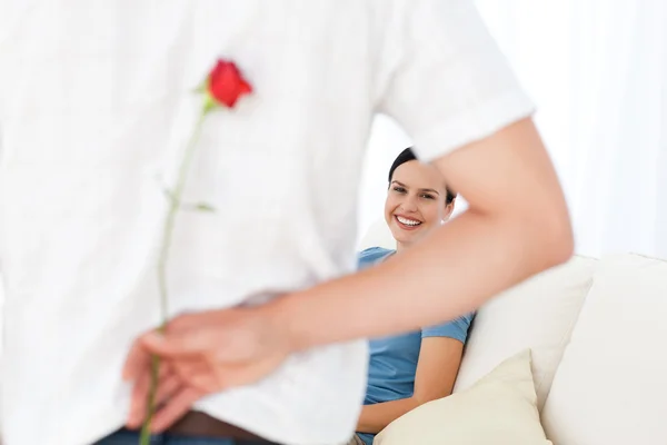 Attentive man hidding a flower behind his back for his girlfrien — Stock Photo, Image