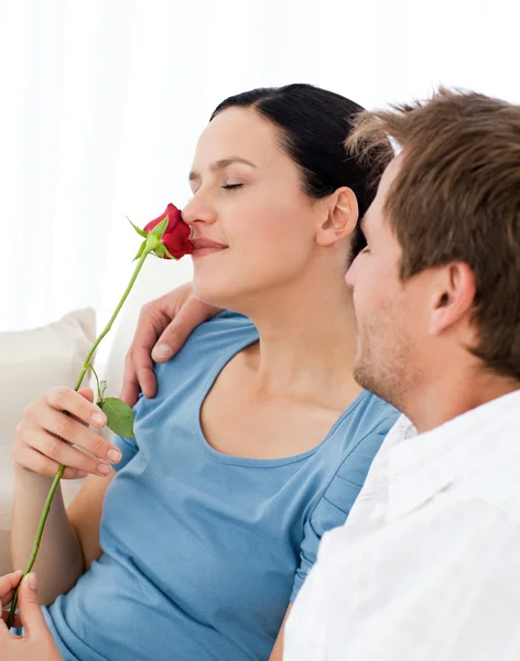 Wwoman piękny zapach róży, siedząc na kanapie — Zdjęcie stockowe