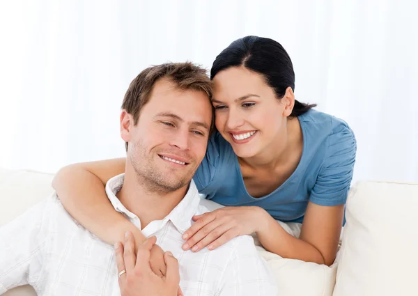 Mujer encantadora abrazando a su novio mientras se relaja en el sofá —  Fotos de Stock