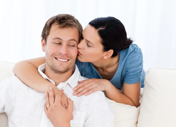 Mulher encantadora beijando seu namorado enquanto relaxa no sofá — Fotografia de Stock