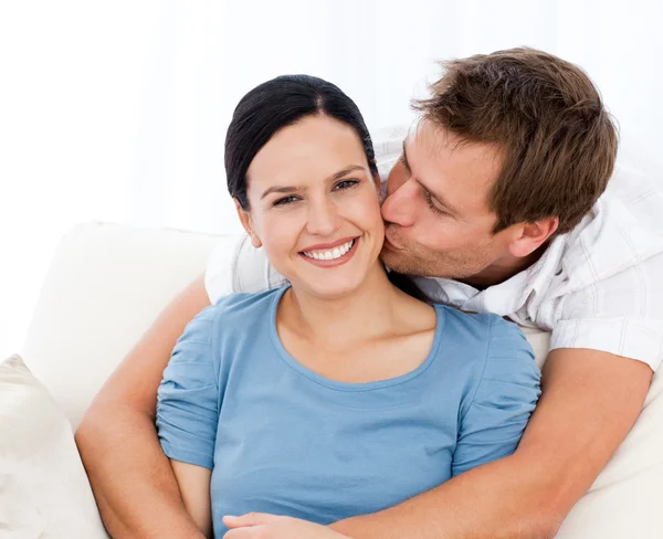 Милый мужчина целует свою девушку, расслабляясь на диване — стоковое фото