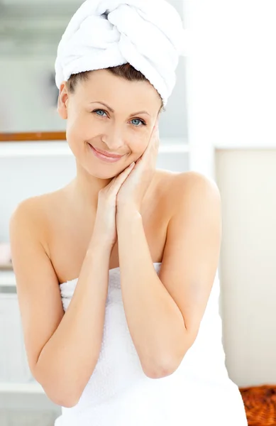 Attractive young woman with a towel putting cream on her face in Royalty Free Stock Photos