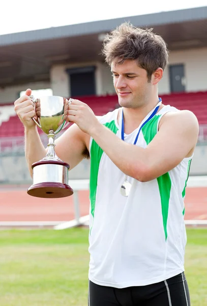 Sporty man holding a cup and a medal standing Royalty Free Stock Images