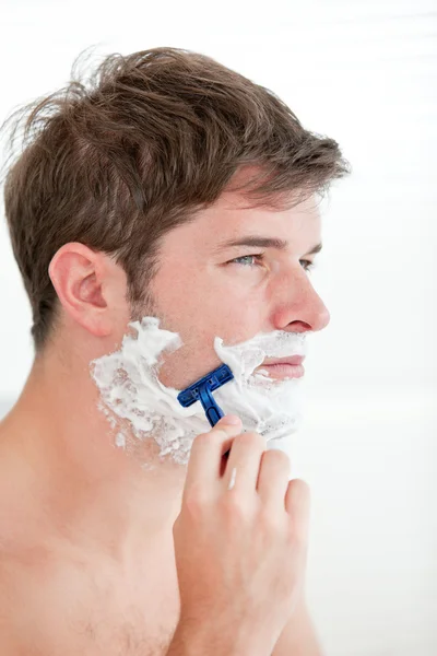 Portrait of a serious man shaving looking away standing in the b Royalty Free Stock Photos