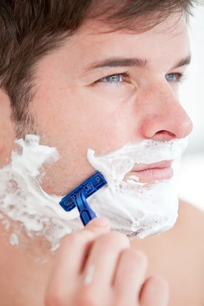 Bright caucasian man shaving in the bathroom Royalty Free Stock Images
