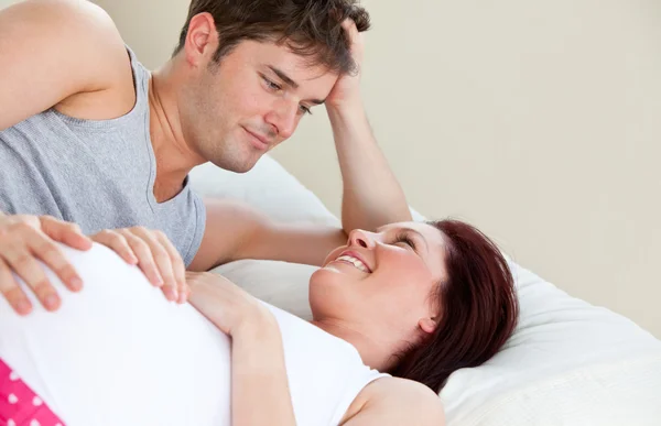 Портрет беременной женщины и лежащего на кровати мужа — стоковое фото