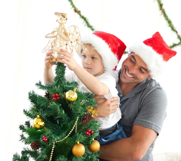 Buon padre aiutare suo figlio a mettere un angelo sul tr Natale Immagine Stock