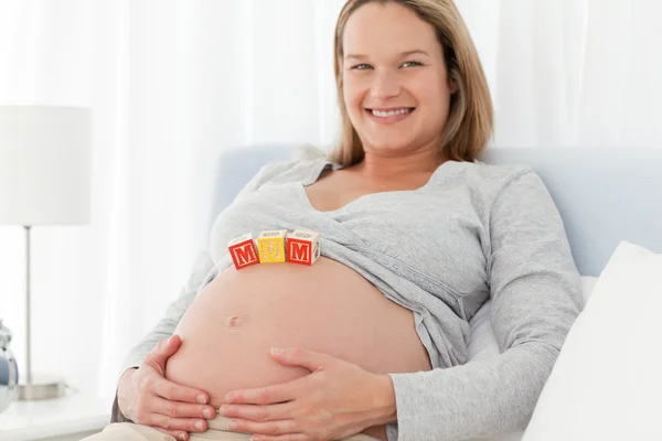 Joyful pregnant woman with mom letters on her belly while relaxi Royalty Free Stock Photos