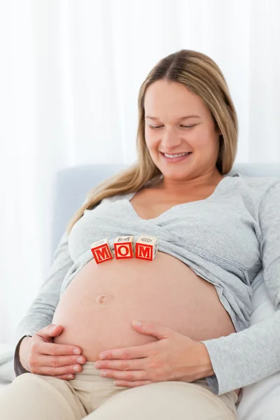 Cute pregnant wife looking at mom letters on her belly Stock Photo