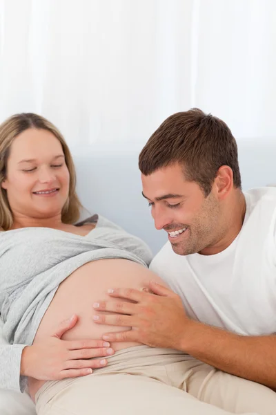 Proud future dad touching the belly of his wife lying on the bed Royalty Free Stock Photos