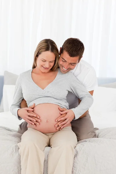 Cute future parents looking at the belly of the woman sitting on Royalty Free Stock Images