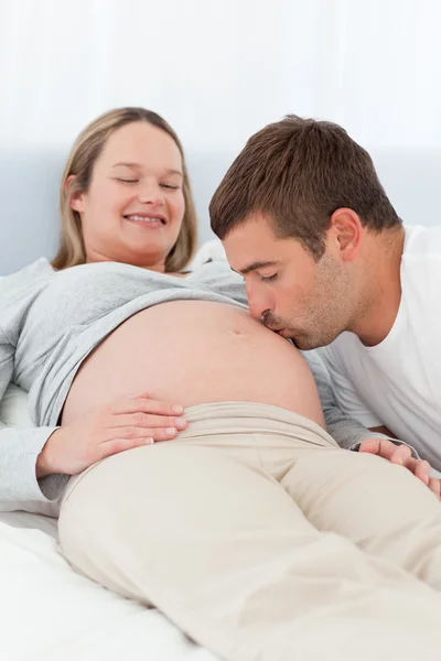 Proud future dad kissing the belly of his wife Stock Image
