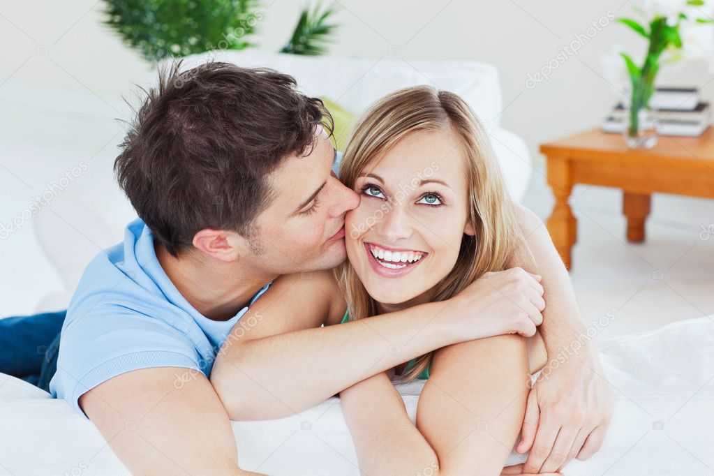 Handsome Man Kissing His Joyful Girlfriend Both Lying On The Sof Stock