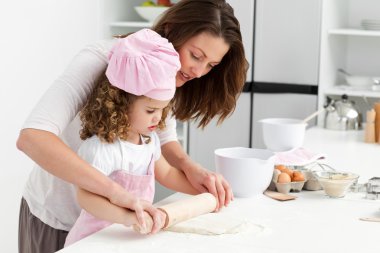 Mother and daughter using a rolling pin together clipart