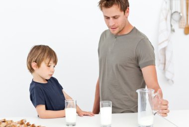 Cute dad and son drinking milk together clipart