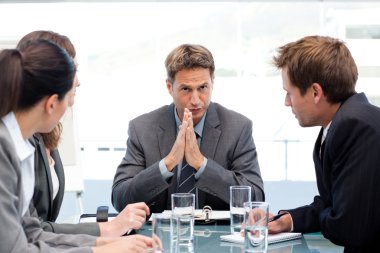 Serious manager talking to his team during a meeting clipart
