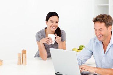 Cheerful couple looking at something on internet while drinking clipart