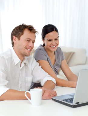 Lovely couple laughing while looking at a video on the laptop clipart