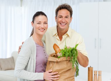 Portrait of a couple coming back from the market with vegetables clipart