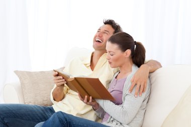 Man laughing while looking at a photo album with his girlfriend clipart