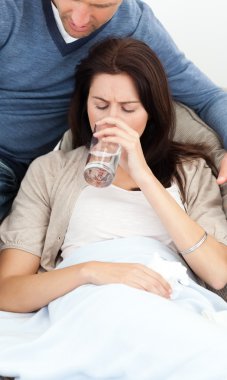 Sick woman drinking water lying on the sofa clipart