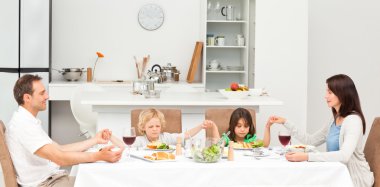 Concentrated family praying before having lunch clipart