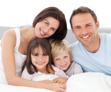 Lovely family sitting together on the bed clipart