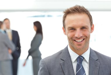 Happy businessman posing in front of his team clipart