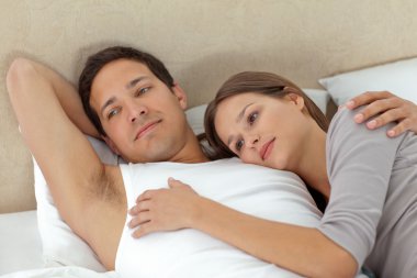 Pensive couple lying in each other's arms clipart