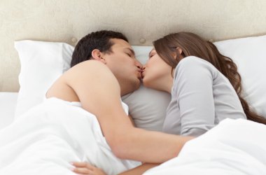 Lovely couple kissing in each other's arms on the bed clipart