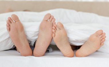 Close up of couple's feet while relaxing in their bed clipart