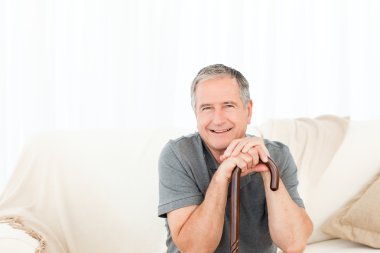 Mature man with his walking stick on his bed clipart