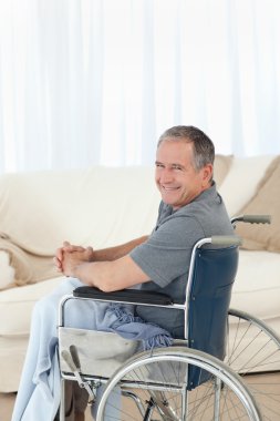 Mature man in his wheelchair looking at the camera clipart