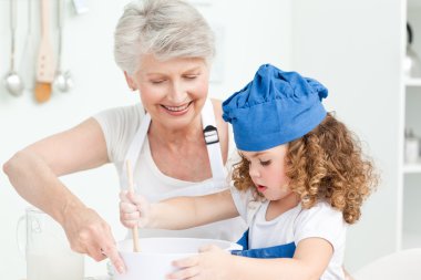 A little girl baking with her grandmother clipart