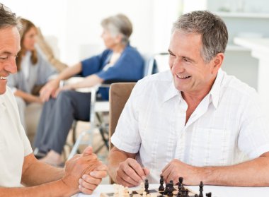 Men playing chess while their wifes are talking clipart