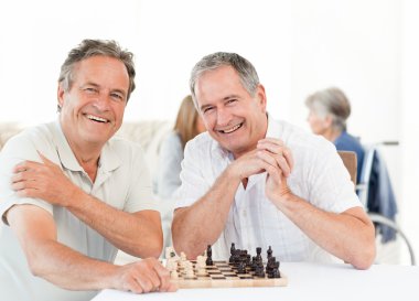 Men playing chess while their wifes are talking clipart