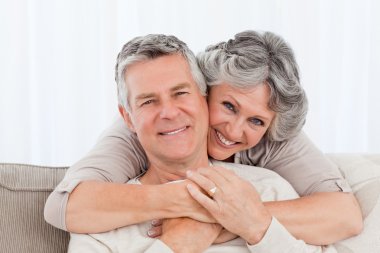 Mature couple looking at the camera at home clipart