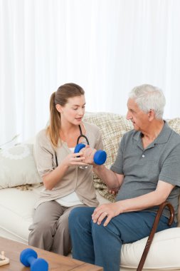 Lovely nurse helping her patient to do exercises clipart