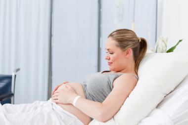 Pregnant young woman on a hospital bed clipart