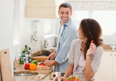 Beautiful woman looking at her husband who is cooking clipart