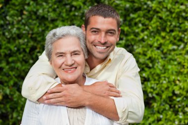 Man hugging his mother in the garden clipart